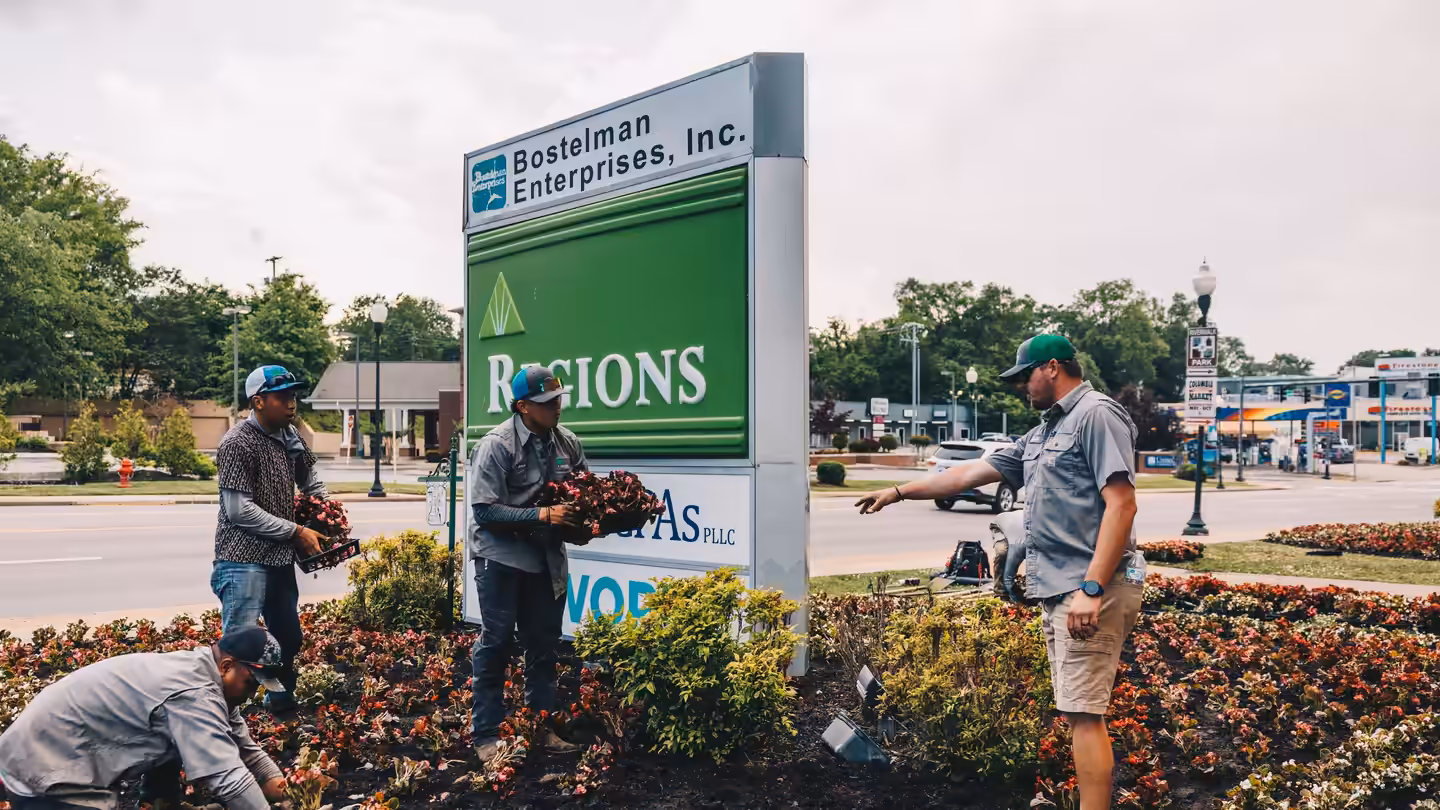 Three Richardson crew members planting seasonal color around a downtown Columbia business sign