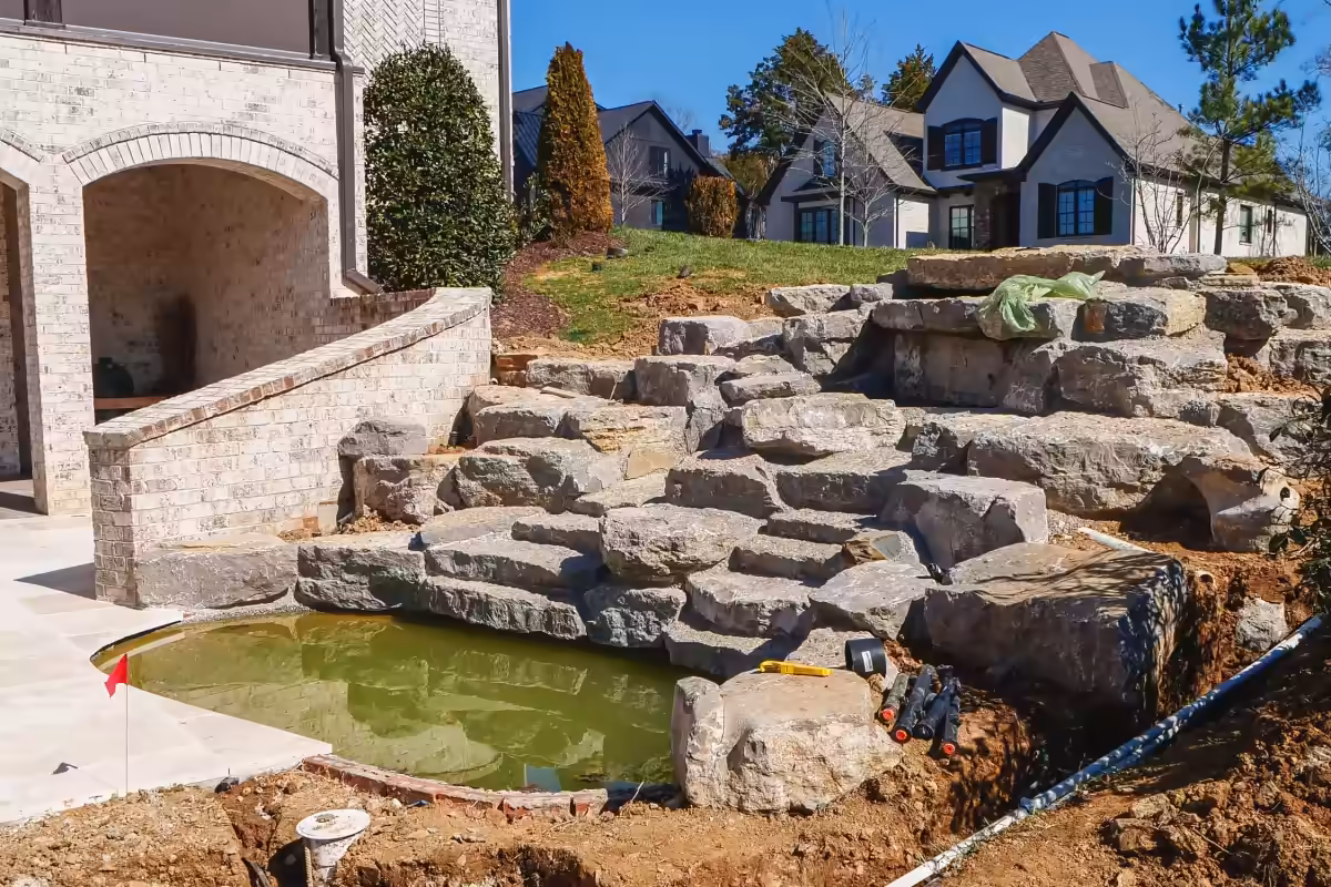Stacked boulders step down to the pond of the new water feature.