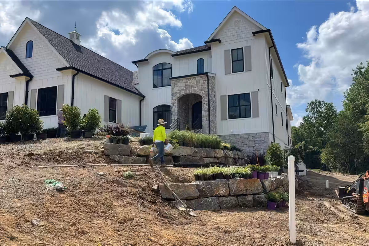 Stacked stone retaining walls and steps below a new home