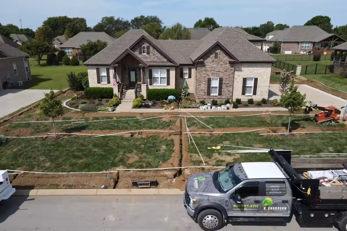 Irrigation trenches crossing the front lawn of a brick home
