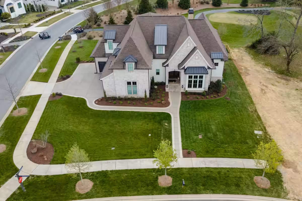 A finished front yard from above: walks, beds, young trees and new sod