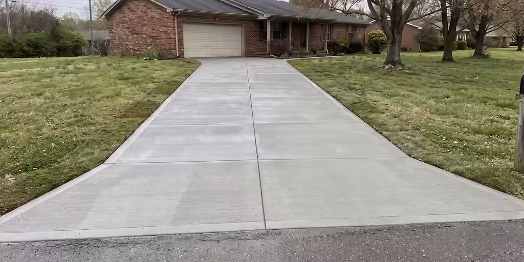 After: The same driveway replaced with new broom-finished concrete, clean control joints and a new apron
