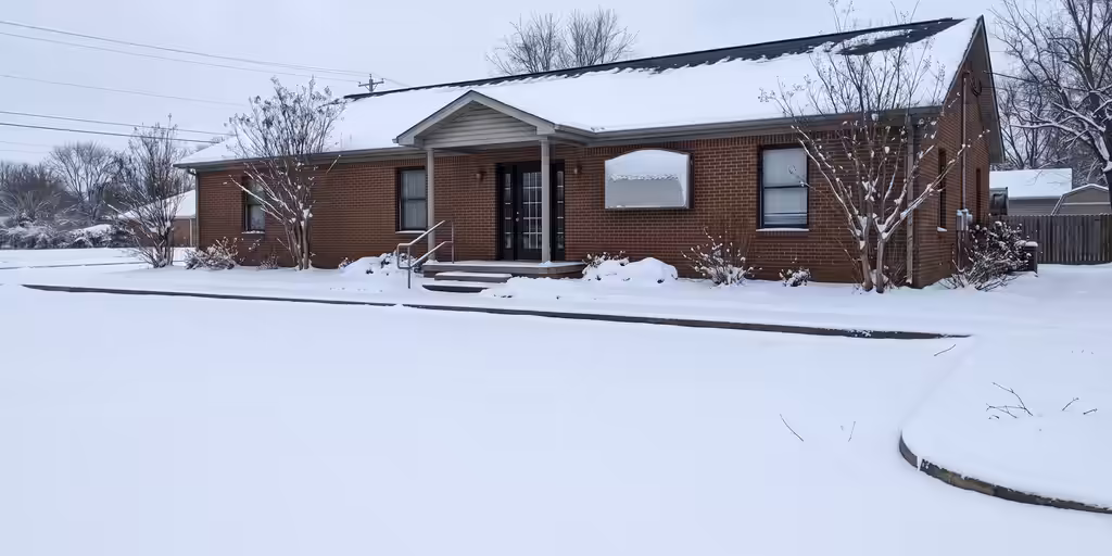 Before: Snow-covered parking lot, curbs and front walk of a one-story brick office building