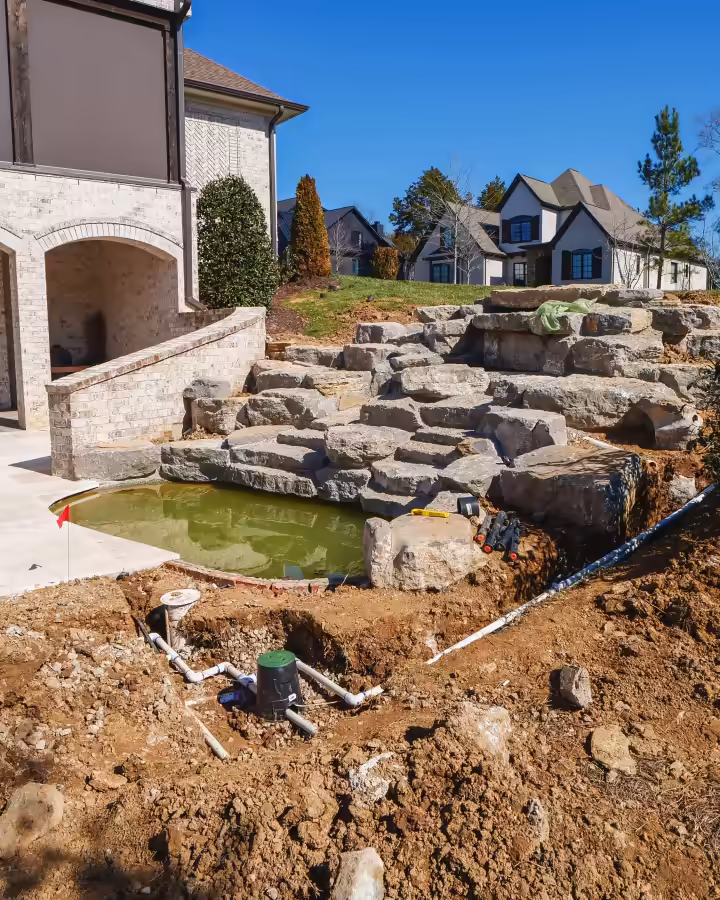 Stacked boulders forming a water feature beside a Middle Tennessee home