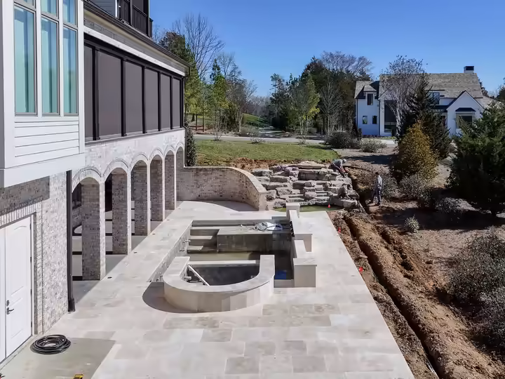 Travertine terrace with a raised spa beside the arched loggias.