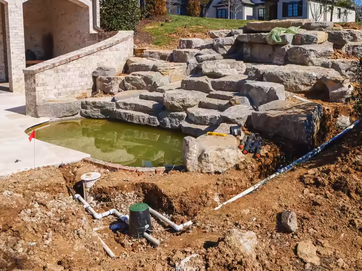 Stacked boulders forming a water feature beside a home