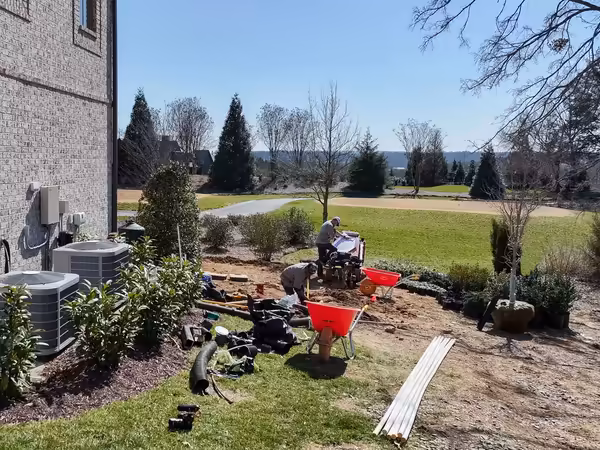 Richardson crew installing drainage and new beds beside a home on a golf course