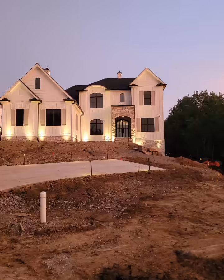 Large Franklin home at dusk with warm landscape uplighting on the facade and new beds
