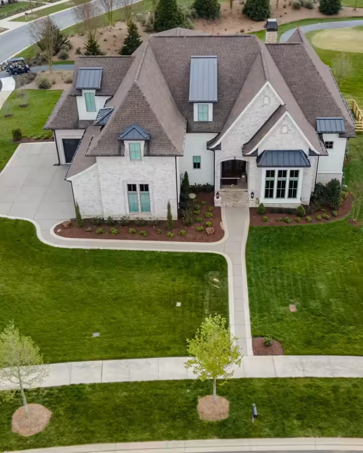 Aerial view of a new home after a Richardson install: fresh lawn, planted beds and young trees along the walk