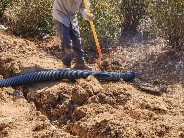 Laying perforated drain pipe in a trench