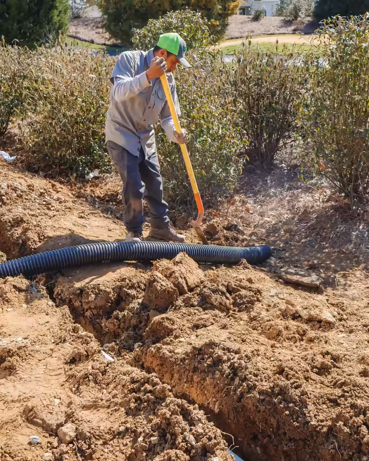 Richardson crew member laying perforated drain pipe in a trench