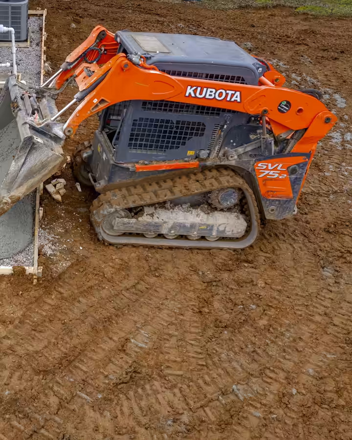 Richardson skid steer grading ground beside a building