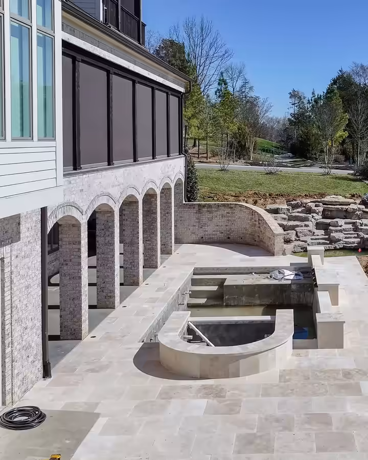 New travertine terrace and raised spa beside arched loggias